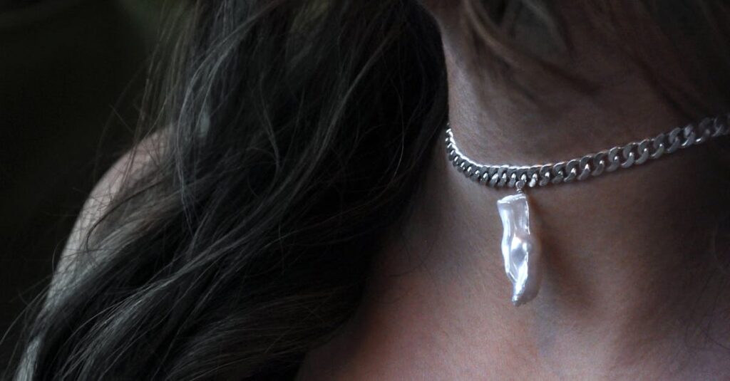 Close-up of a silver pendant necklace worn by a woman, showcasing fine jewelry and fashion.
